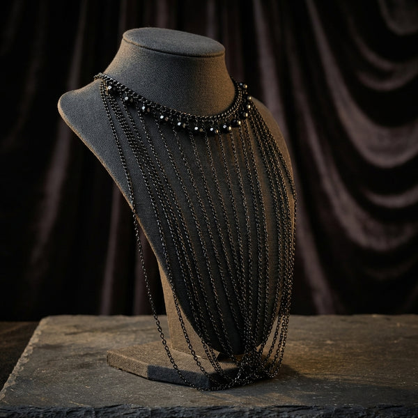 Express black beaded choker necklace with multistrand crossing chains on a mannequin bust against a dark background