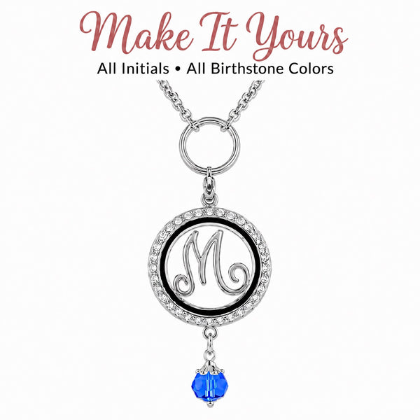 A silver initial Floating Charm Locket necklace with clear rhinestone border, Letter M and a dangling sapphire blue faceted glass birthstone, shown on a white background with the text 'Make It Yours' and 'All Initials • All Birthstone Colors'