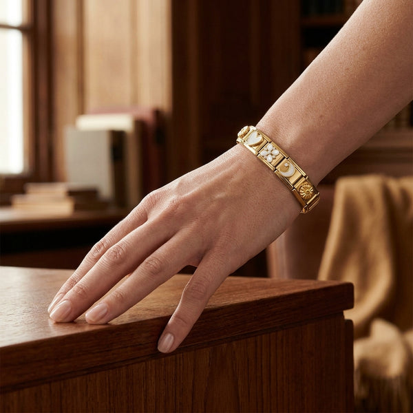 Hand wearing a gold 9mm Italian charm bracelet with assorted white enamel and crystal charms