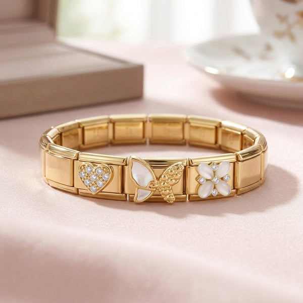 Gold 9mm Italian charm bracelet with heart, butterfly, and flower designs on a pink surface.