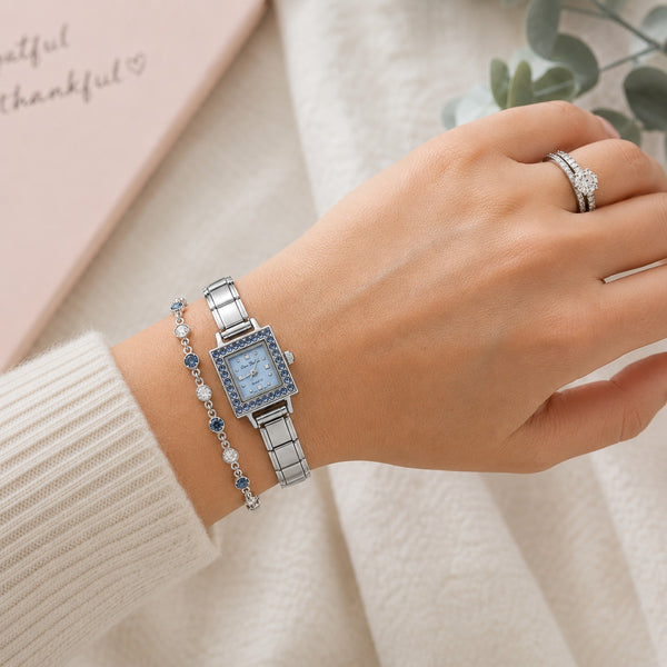 A silver-tone 9mm Italian charm watch with a light blue square dial and blue crystal accents, worn on a woman's wrist alongside a matching blue and silver beaded bracelet. 