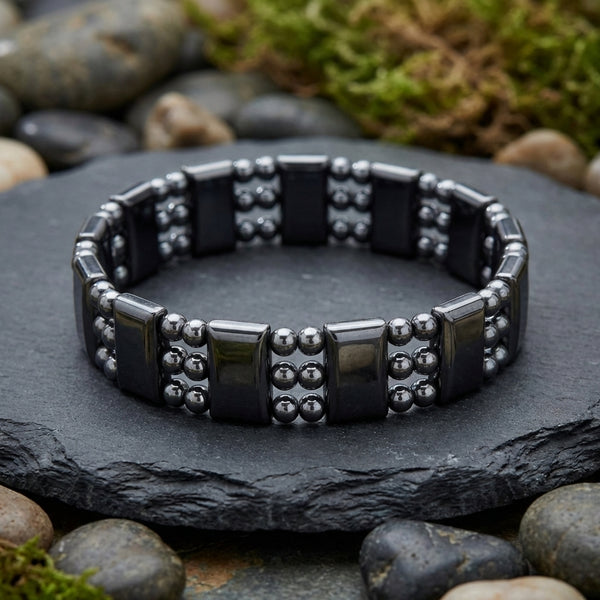 Black hematite magnetic beaded bracelet on a dark stone surface with a natural background