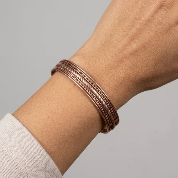 Rope Channel Copper Cuff Bracelet on wrist, gray background