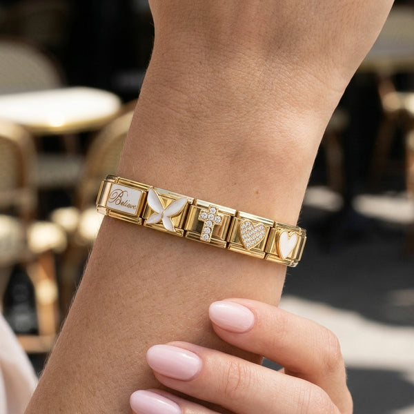 Gold 9mm Italian charm bracelet with various premium charms on a wrist against a blurred background