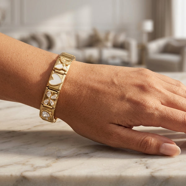 Gold 9mm Italian charm bracelet with heart and bow design on a hand against a blurred indoor background