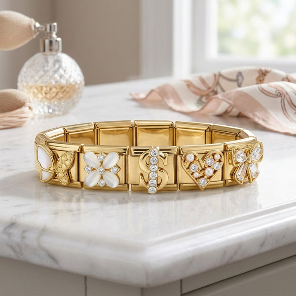 Gold Italian charm bracelet with floral and dollar sign designs on a marble surface