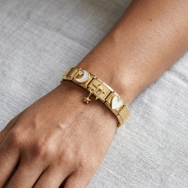 Gold 9mm Italian charm bracelet with heart and star charms on a wrist against a gray background