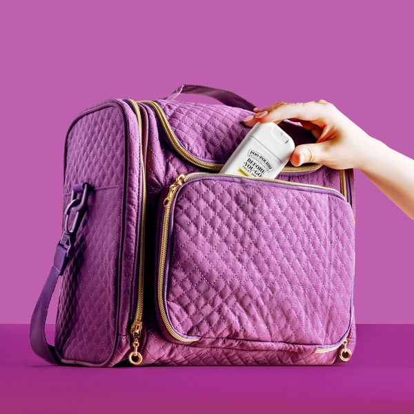 Poo Pourri TSA Approved Pocket Sprayer In Original Citrus. Purple travel bag on purple background.