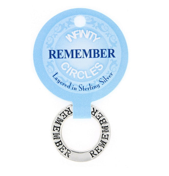 A silver plated infinity circle charm engraved with the word 'REMEMBER' repeated around the circle, attached to a light blue round display card that reads 'INFINITY CIRCLES Layered in Sterling Silver' on a white background.