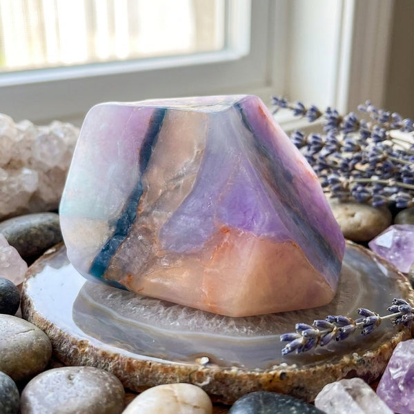 Soapal Gemstone soap on geode display with lavender flowers and pebbles.