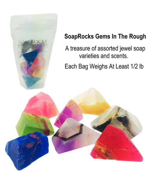 A clear bag with colorful gemstone soap inside, a variety of soap bars scattered in front